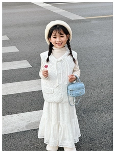 Detail of a blue denim quilted mini bag with a metal chain held by a child model
