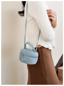 Detail of blue denim quilted mini bag with chain strap and belt buckle closure