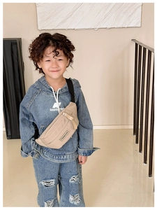 Vue détaillée du sac de poitrine beige pour enfant avec sangle noire réglable