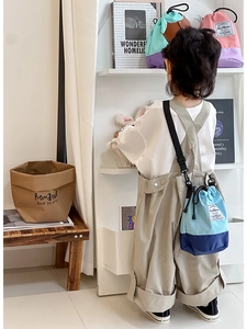 Detail of adjustable straps and drawstring closure on kids' contrast bucket bag