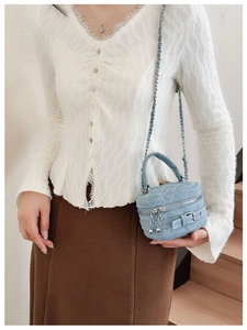 Close-up of mini blue denim crossbody bag featuring quilted patterns and chain strap