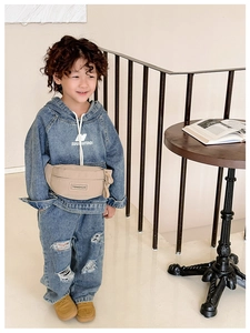 Sac banane enfant à la mode avec écusson lettré porté sur un sweat à capuche en jean