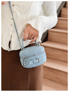 Detail of light blue quilted denim mini crossbody bag with silver chain strap and zipper