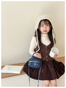 Detailed close-up of dark blue denim quilted bag with silver chain on a child model
