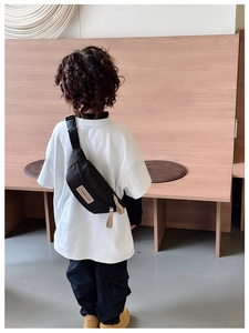 Vue de dos d'un enfant portant un sac de poitrine en toile noire avec sangle ajustable