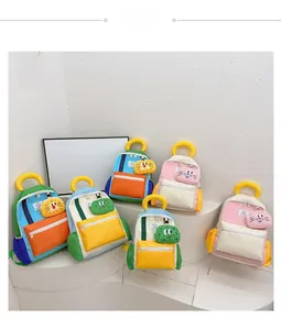 Detail view of colorful cartoon backpacks for kids with 3D animal charms on white stands