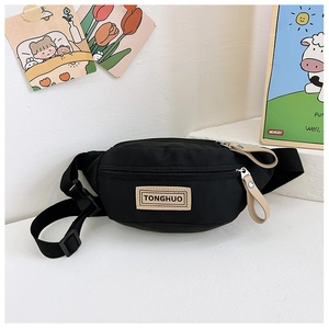 Détail du sac banane en toile noire avec écusson en cuir et sangle réglable à boucle