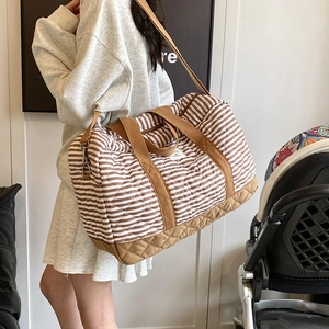 Sac à langer matelassé à rayures avec bandoulière réglable porté par un mannequin
