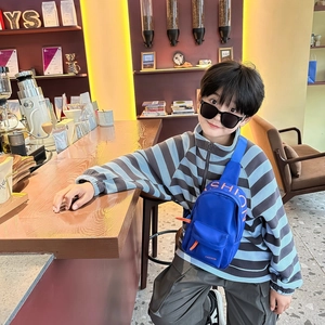 Kids royal blue chest bag with red fashion lettering in a cozy cafe setting