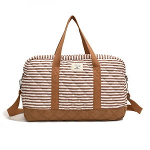 Sac à langer matelassé à rayures avec poignées marron et écusson sur fond blanc pur