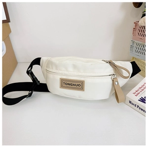 Détail du sac de poitrine blanc pour enfant en toile avec écusson cuir et sangle noire