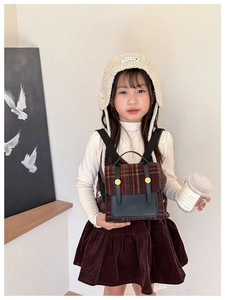 Close-up of retro plaid kids backpack with leather patchwork and golden buckles