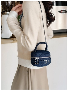 Model wearing a mini dark blue denim quilted chain bag in a cozy cafe setting