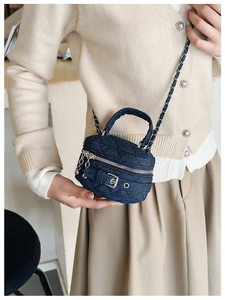 Detailed view of quilted denim box bag with silver hardware and chain strap accents