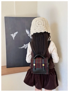 Detail of vintage plaid kids backpack with leather trim and gold decorative buttons