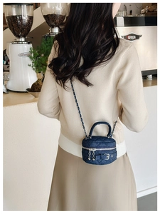 Close-up of mini blue denim crossbody bag with quilted pattern and gold chain strap
