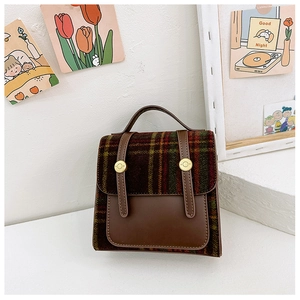 Detail of vintage plaid kids backpack with brown leather straps and gold metal buckles
