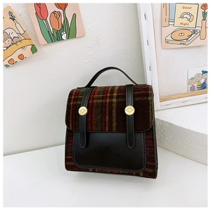 Detail view of British vintage kids backpack featuring red-green plaid tweed and leather