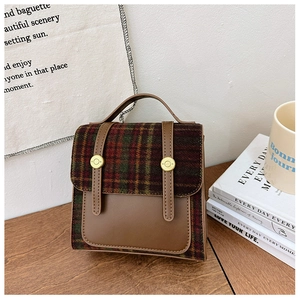 Detail of vintage plaid tweed child backpack with brown leather and gold buckle