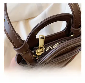 Close-up of golden zipper hardware and stitching on a dark brown leather handbag