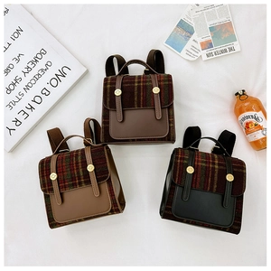 Three mini vintage plaid backpacks in black, brown and beige colors on a white fabric