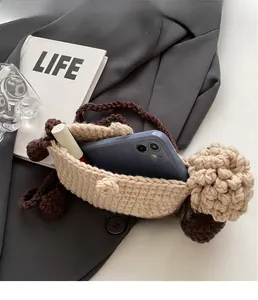 Macro detail of handmade crochet mini sheep bag showing storage for phone and lipstick