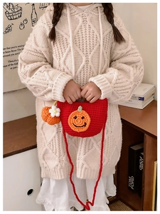 Detail of red handmade knit shoulder bag with pumpkin face design for children