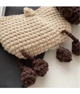 Detail of handmade crochet sheep bag showing beige knit texture and brown decorative spheres