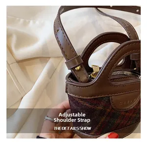 Detail showing brown plaid mini bucket bag with leather handles and adjustable strap