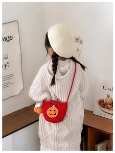 Kid back view wearing red crochet pumpkin shoulder bag with festive pumpkin charm detail