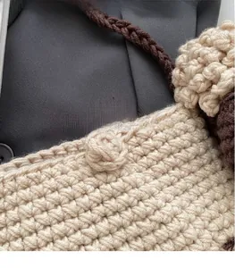 Macro detail of handmade beige and brown crochet sheep bag with thick knit texture
