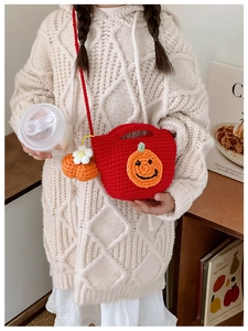 Detail of red handmade crochet crossbody bag with orange pumpkin face and mini charm