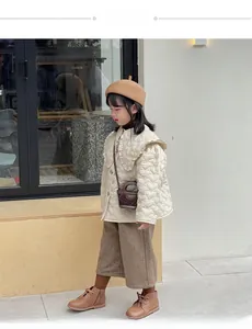 Close-up of heart-shaped quilted pattern and ruffled collar on kids' cream jacket