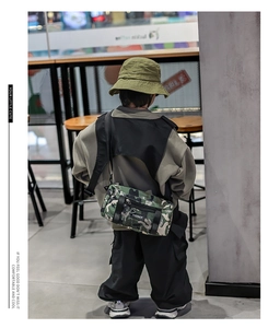 Detail der Kinder-Umhängetasche in Camouflage mit Logo und breitem Gurt
