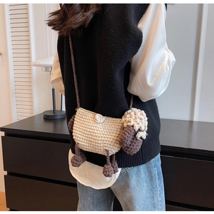 Detail view of handmade crochet sheep crossbody bag with woven shoulder strap on model