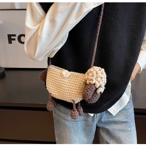 Detail of a handmade crochet sheep crossbody bag with a 3D knit design and woven strap