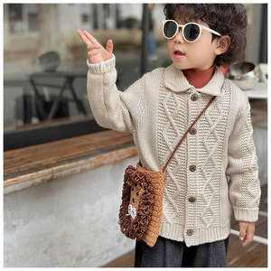 Detail of a handmade crochet lion shoulder bag paired with a beige knit cardigan
