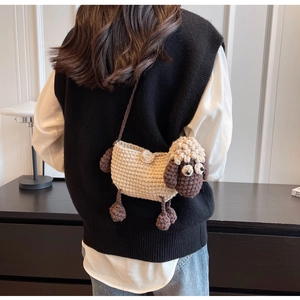 Close-up of a handmade sheep crochet crossbody bag worn with a casual knit vest