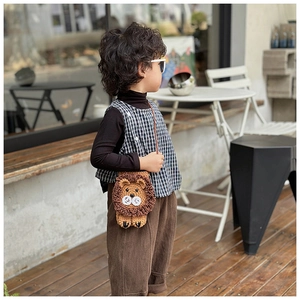 Close-up of handmade crochet lion crossbody bag worn by a child in outdoor setting