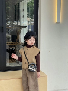 Detail of child wearing khaki vest and brown trousers with a quilted mini tote bag
