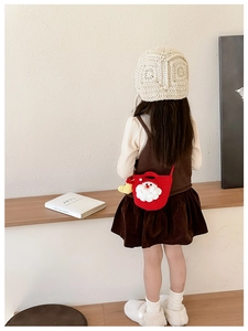 Detail of a handmade red crochet Santa crossbody bag and cream knitted hat for kids