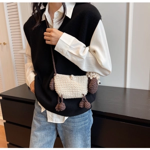 Detail shot of a handmade crochet sheep crossbody bag worn by a model in casual attire