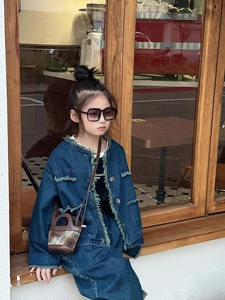 Detail shot of a brown plaid patterned bucket bag paired with kids denim outfit