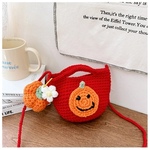 Detail of red handmade knit children bag with orange pumpkin face and flower charm