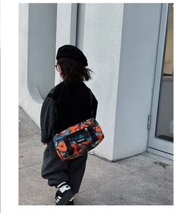 Kind trägt eine bunte florale Zylindertasche in einer modernen Outdoor-Streetstyle-Aufnahme