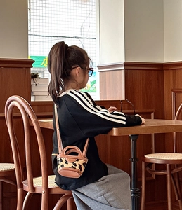 Close-up of mini bucket bag with leopard print and brown leather trim on wooden table