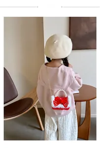 Détail d'un sac en peluche rouge pour enfant avec nœud à pois et poignée en perles