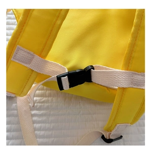 Detail of adjustable safety chest strap buckle on a yellow oxford fabric school backpack
