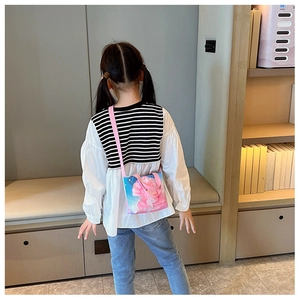 Rear view of a child wearing a small pink floral canvas handbag in a cozy home setting
