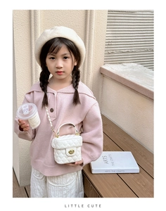 Girl wearing a white quilted bucket bag with gold lock and chain strap outdoors